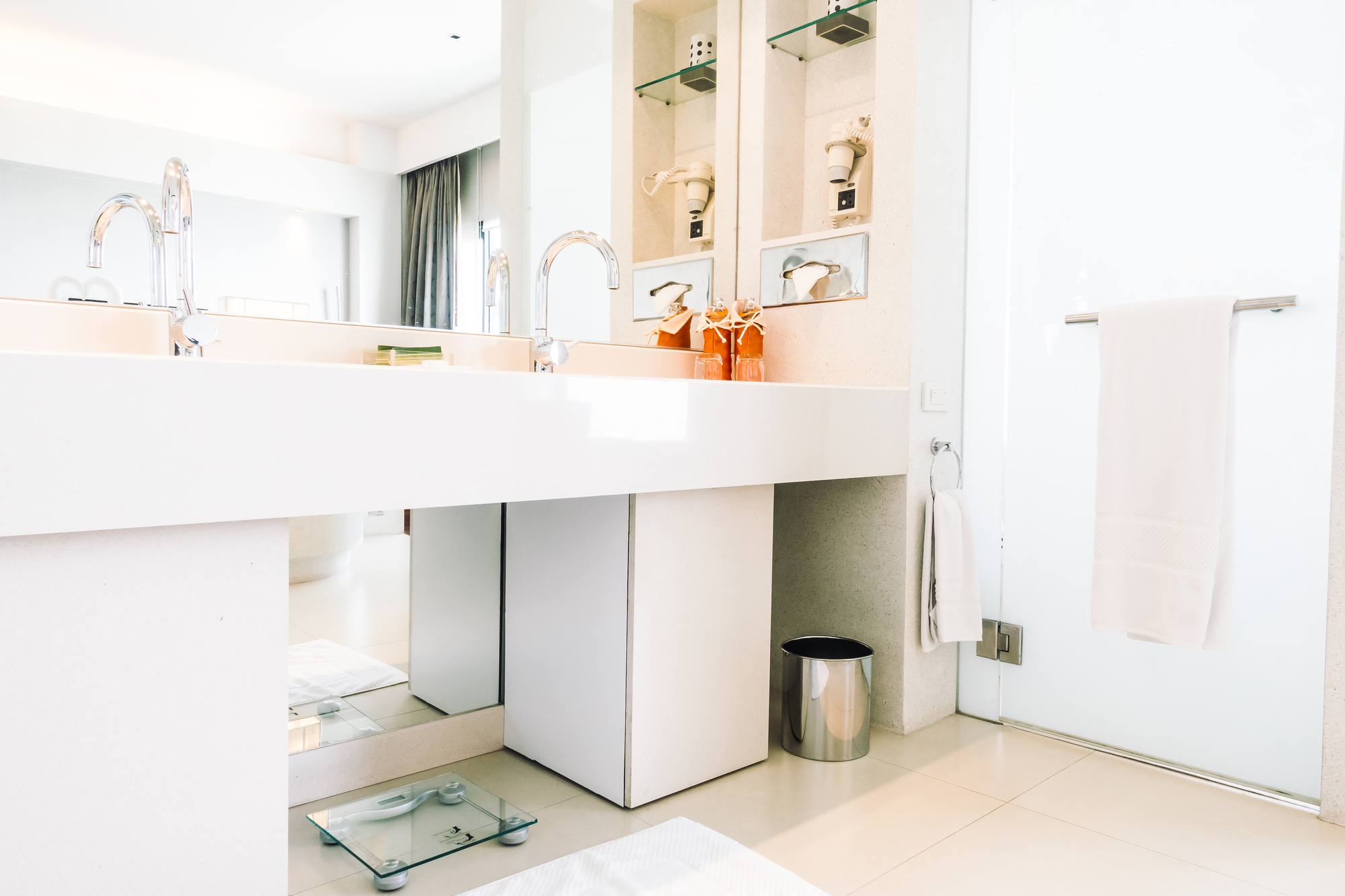 A white remodeled bathroom vanity with two sinks and a large mirror.