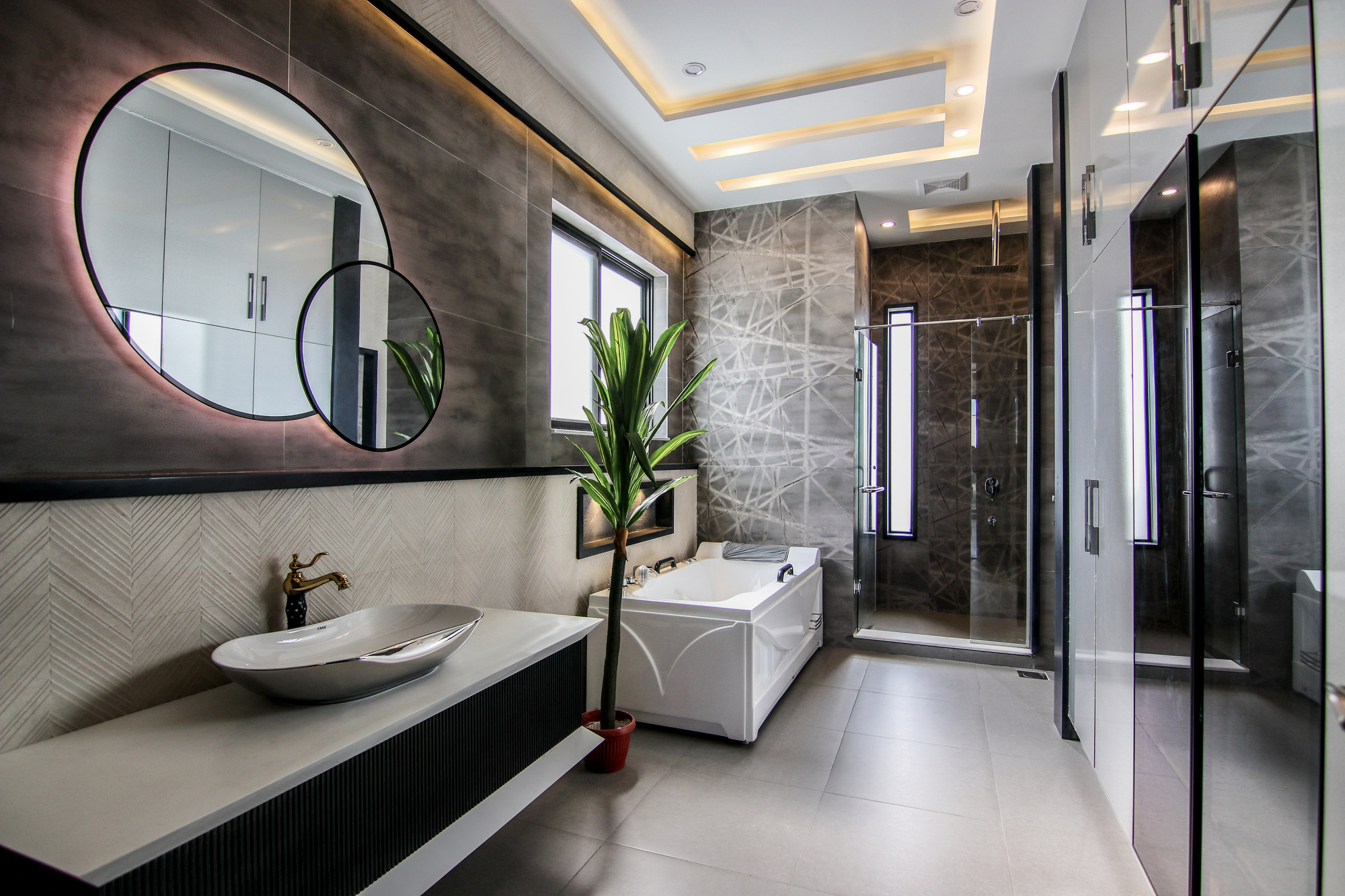 A modern bathroom with a walk-in shower- a white bathtub, and circular mirrors on the wall.
