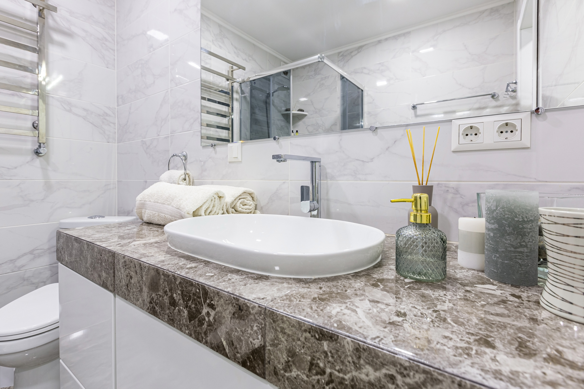 A bathroom with black floors and walls, a white freestanding bathtub, and a wood vanity with large windows.