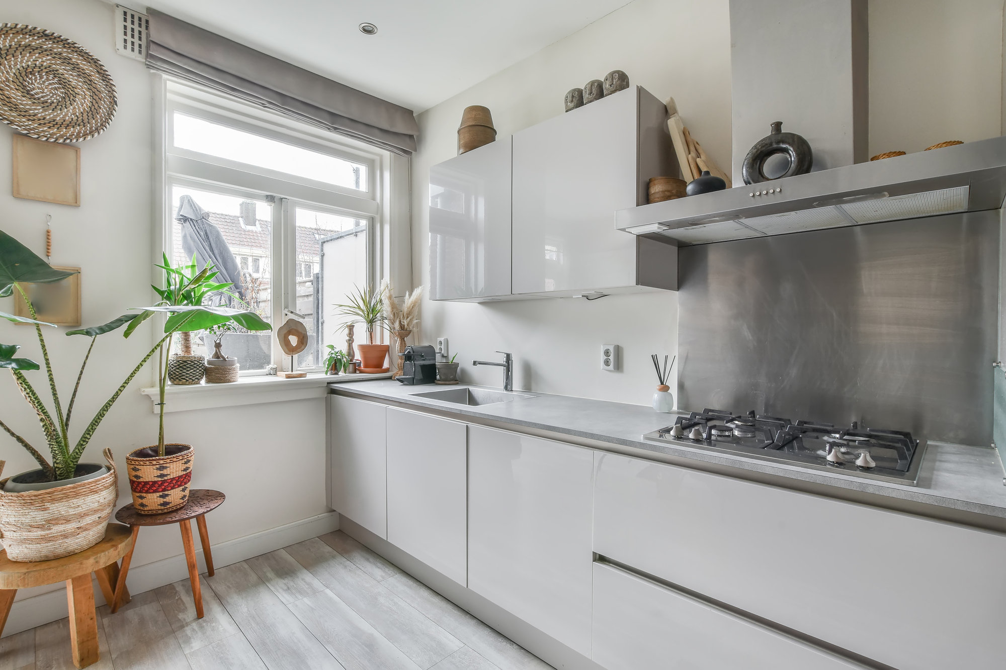 A spacious kitchen in a home with white countertops, white cupboards, and plants