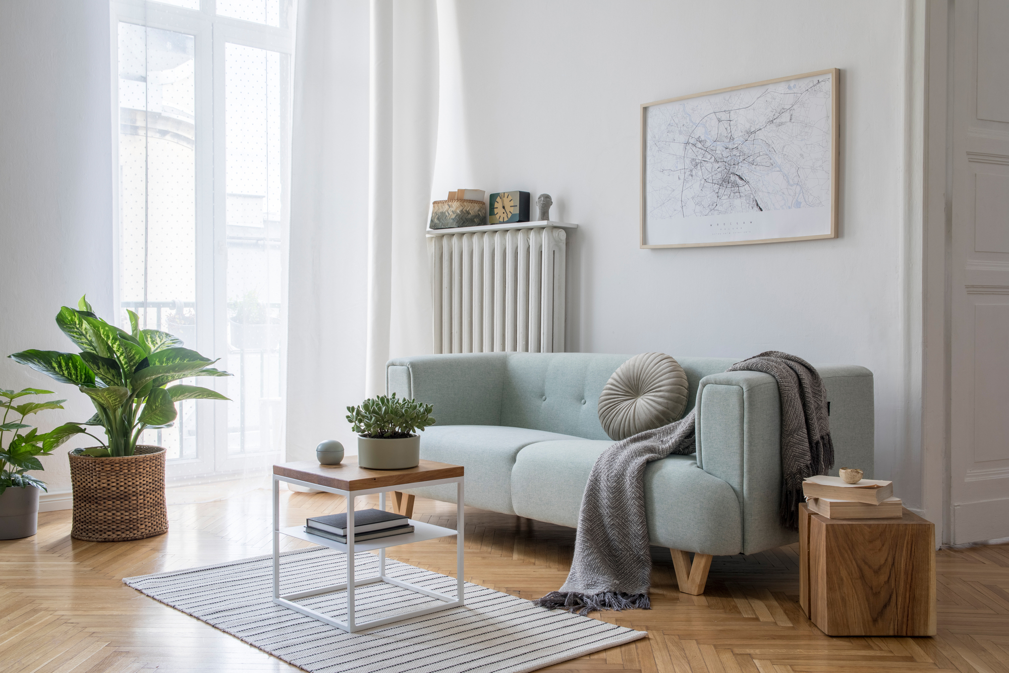 A living room with white walls, a gray couch, a small table, and a gray rug with hardwood flooring.