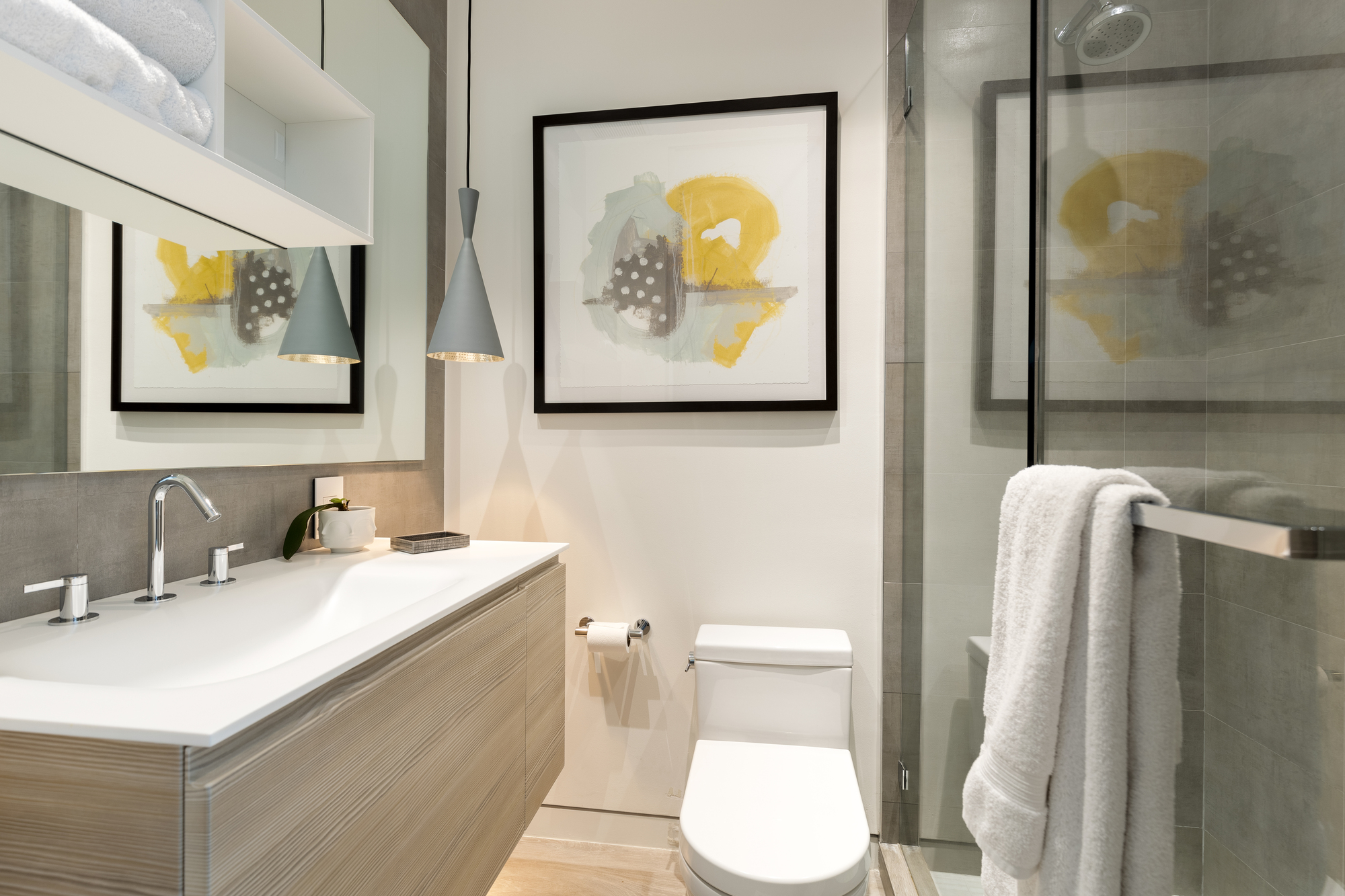 A bathroom with a sink, a white countertop, a white toilet, and a walk-in shower.