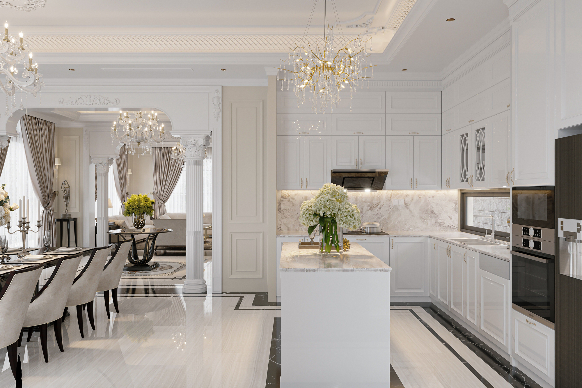 A luxury kitchen with white walls, white cabinets, an island with flowers, and chandeliers hanging from the ceiling.