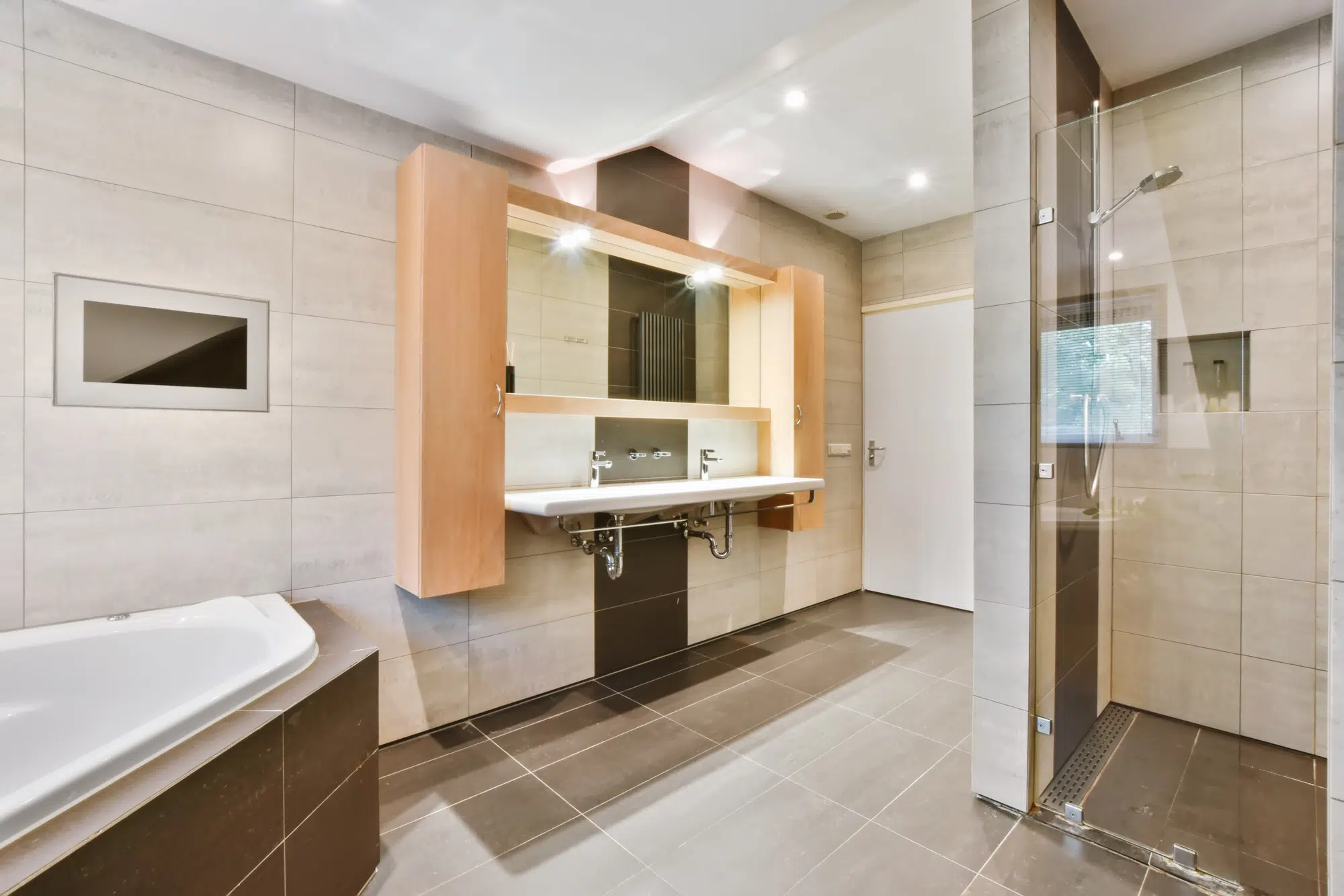 A bathroom with tile flooring, an elevated wooden vanity, and a walk-in shower with a glass door.