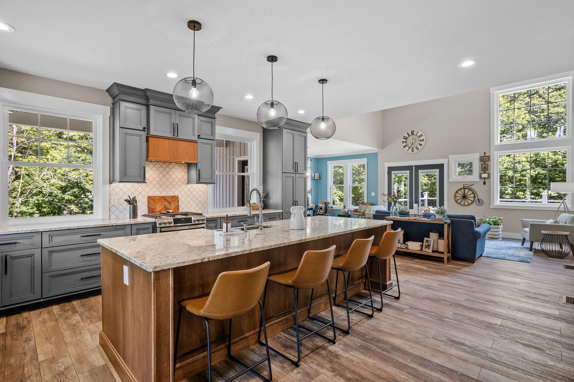 An open kitchen with gray cabinets and a wood island with a marble countertop.