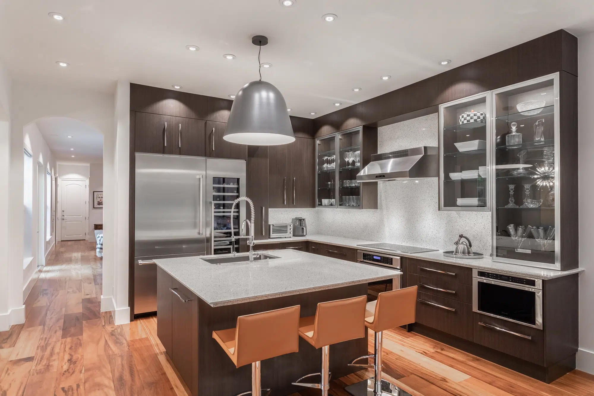 A modern kitchen with gray cabinets, glass cabinets, and a gray island with a marble countertop.