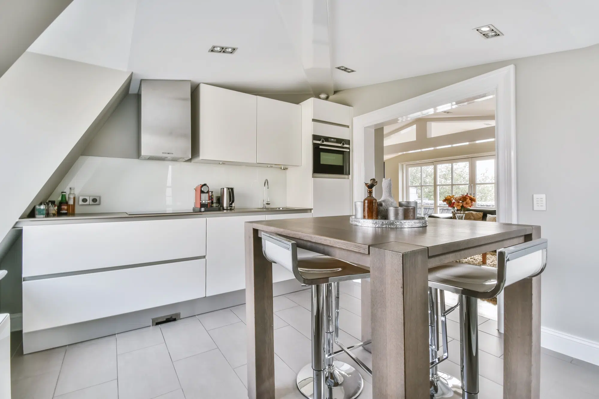 A modern kitchen with white cabinets and a table with high chairs.