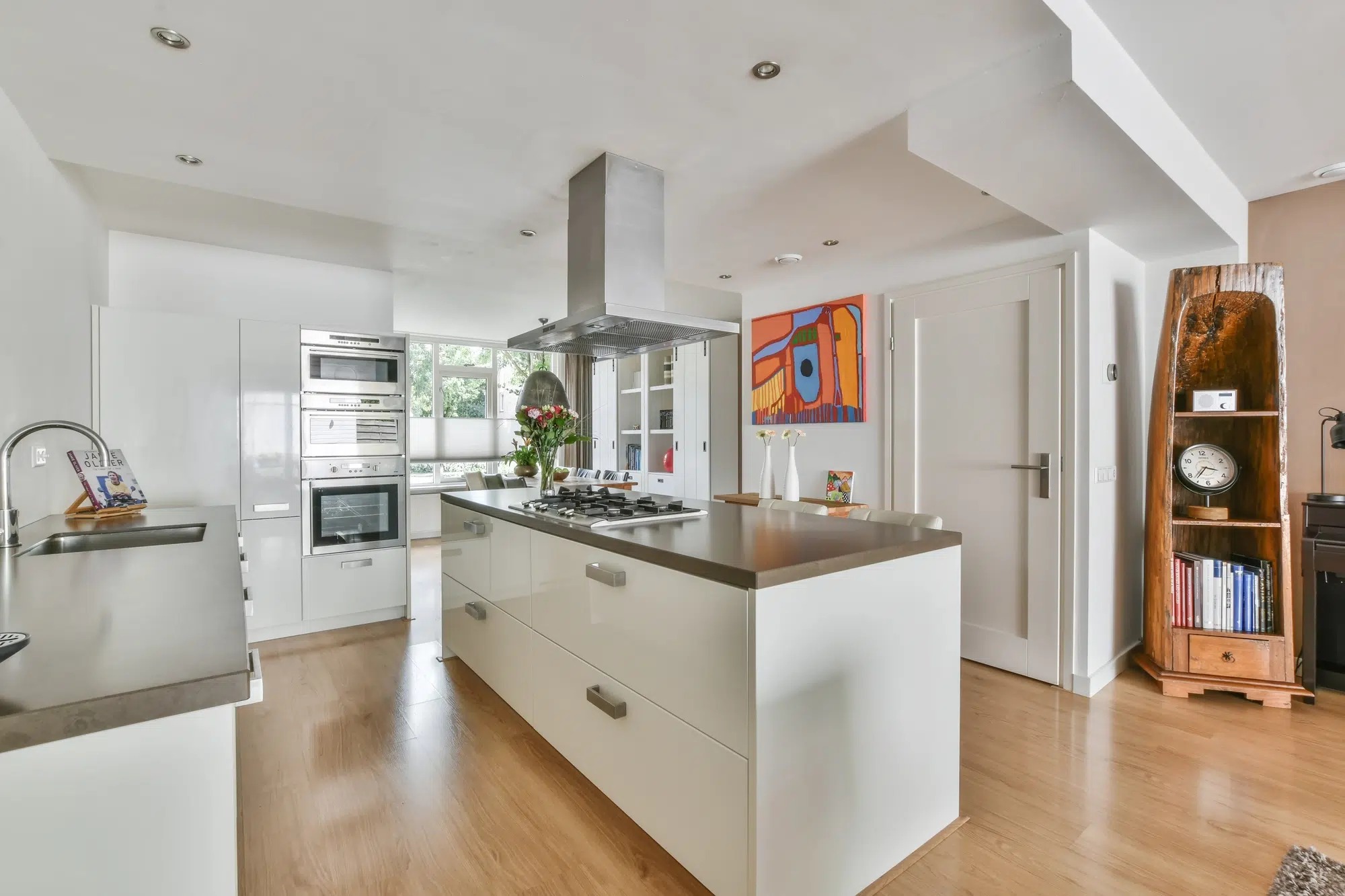 A white kitchen with dark countertops and a white island with a stove on top.