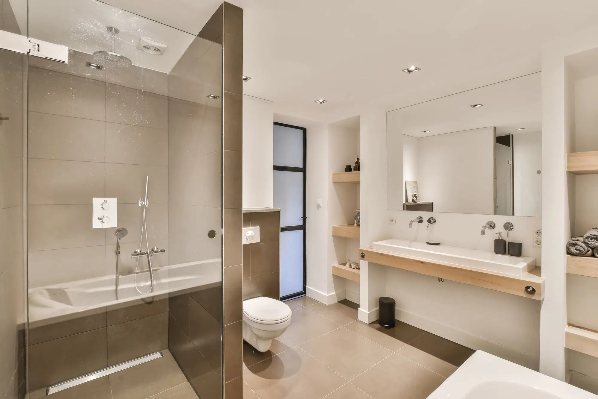A bathroom with a white sink, a white toilet, white walls, and a walk-in shower with a glass door.