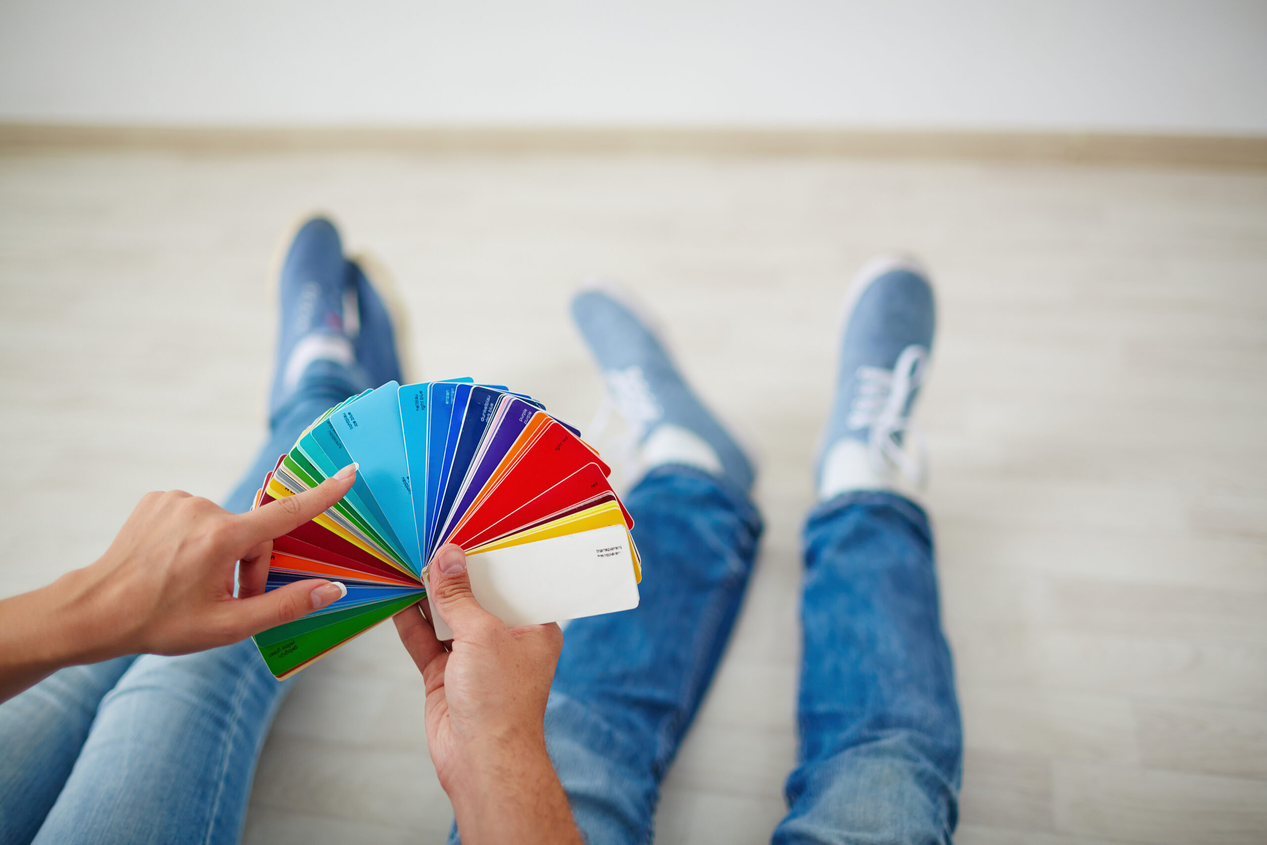 A pair of hands holding paint swatches with vibrant colors.