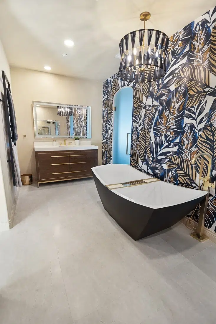 Spacious bathroom with a large built-in oval bathtub, beige tile floors, a long white vanity with dual sinks, arched openings, and mirrored walls.
