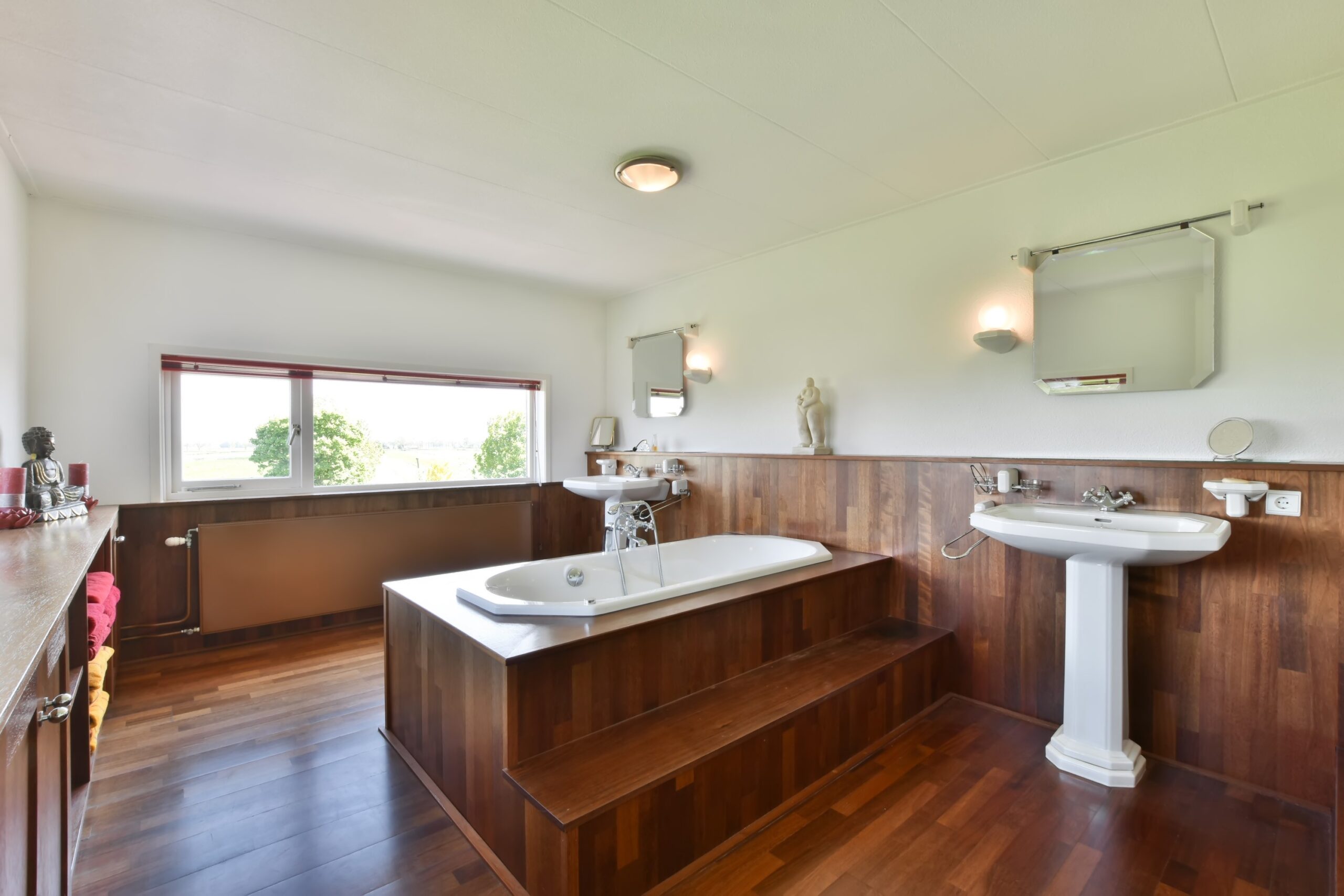Stylish bathroom remodel featuring a luxurious corner soaking tub with tiled steps, dual-sink vanity with marble countertop, and soft ambient lighting.