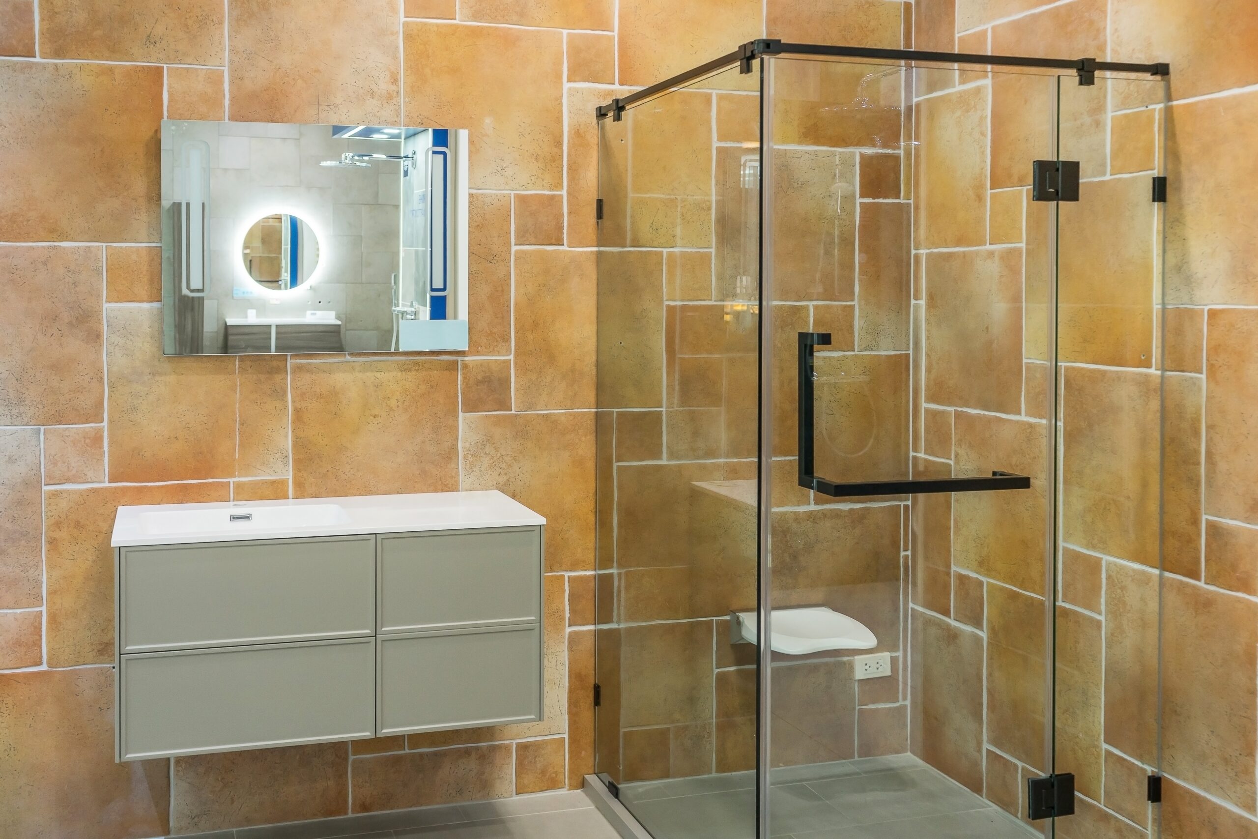 Beautiful Acrylic Showers In Fullerton, CA | EGM Construction A shower with glass doors, tan shower bottom, and tan shelving built into the shower.