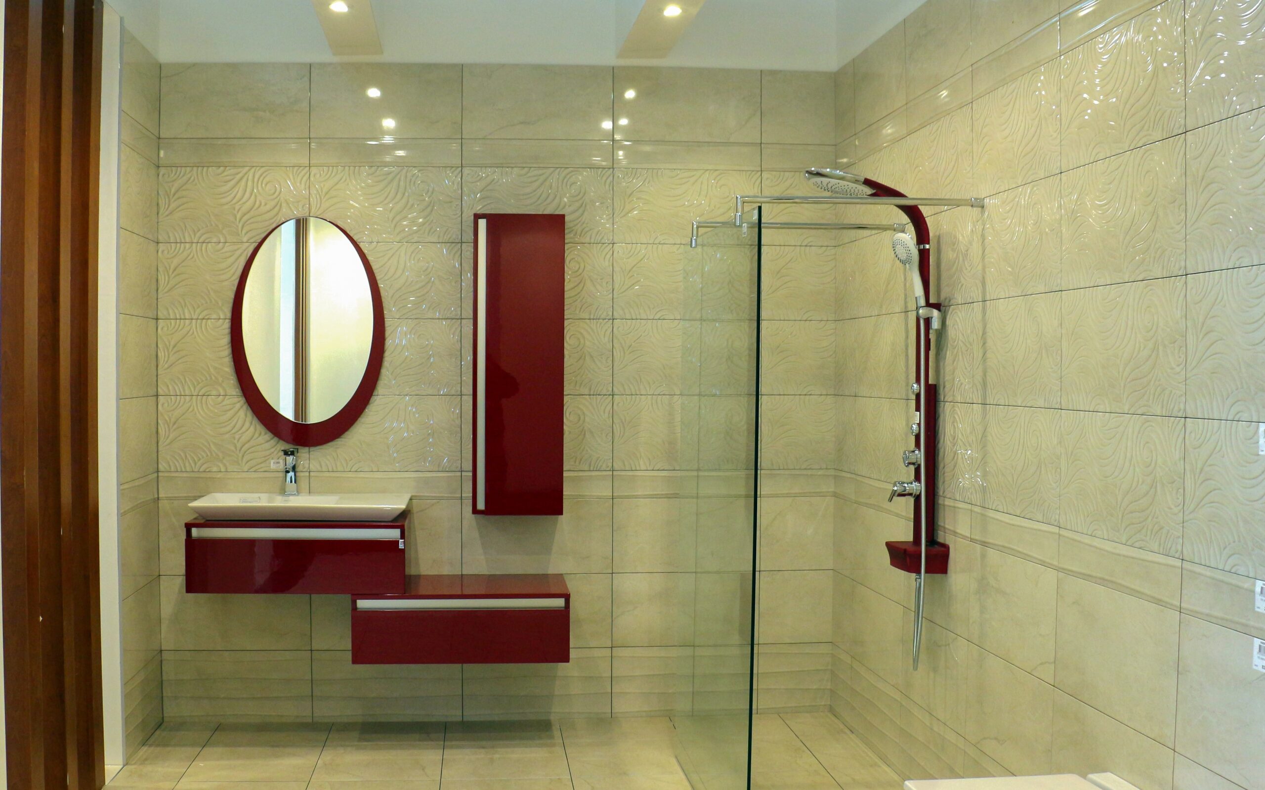 Modern acrylic shower remodel with frameless glass enclosure, decorative wall panels, rainfall shower system, and floating red vanity.