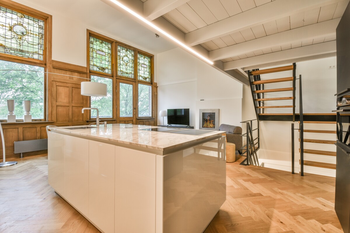 Rustic home remodel with open dining area, wood beam ceiling, updated kitchen, black appliances, warm wood finishes, and adjoining living room.