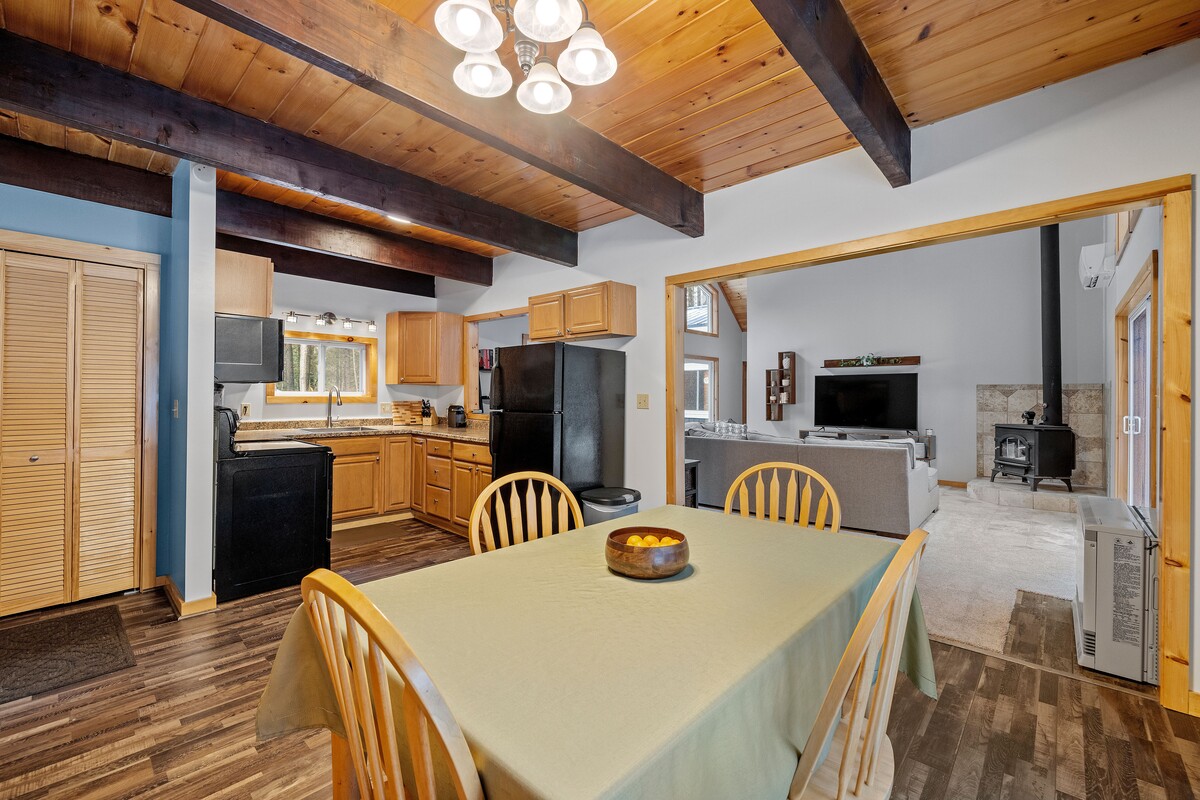 Elegant home remodel featuring a modern kitchen with waterfall island, hardwood floors, open staircase, vaulted beam ceilings, and large stained-glass windows.