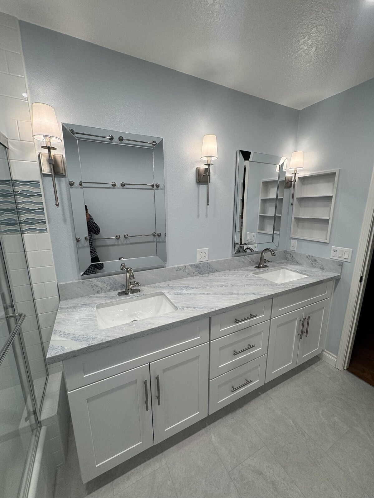 A beautifully updated double vanity with marble countertops and modern light fixtures showcases the stunning results of a professional bathroom remodeling project.
